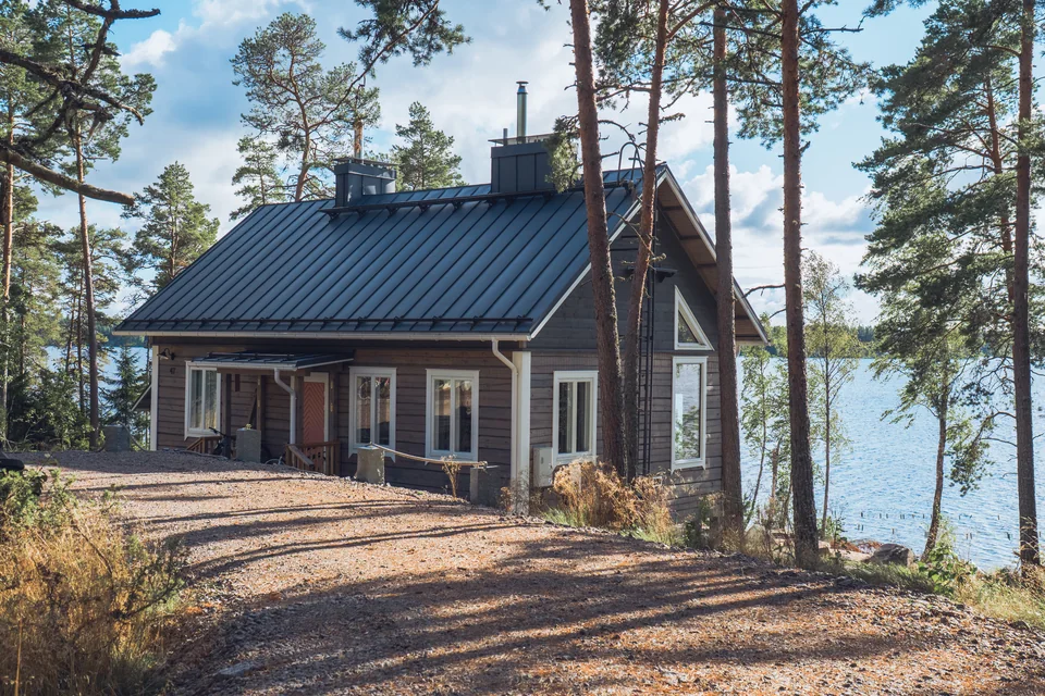 Hirsirakennus järven rannalla mäntymetsässä